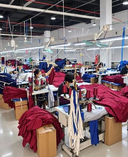 Sewing workshop with operators producing burgundy and navy uniforms
